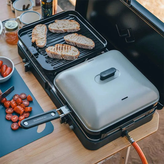 Portable grill with bread slices being grilled on a wooden table.