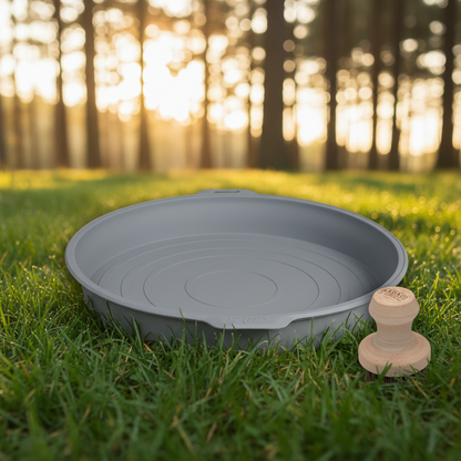 A grey round silicone wash basin with a small wooden-handled brush with dark bristles.