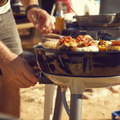 Person grilling food on a portable grill outdoors